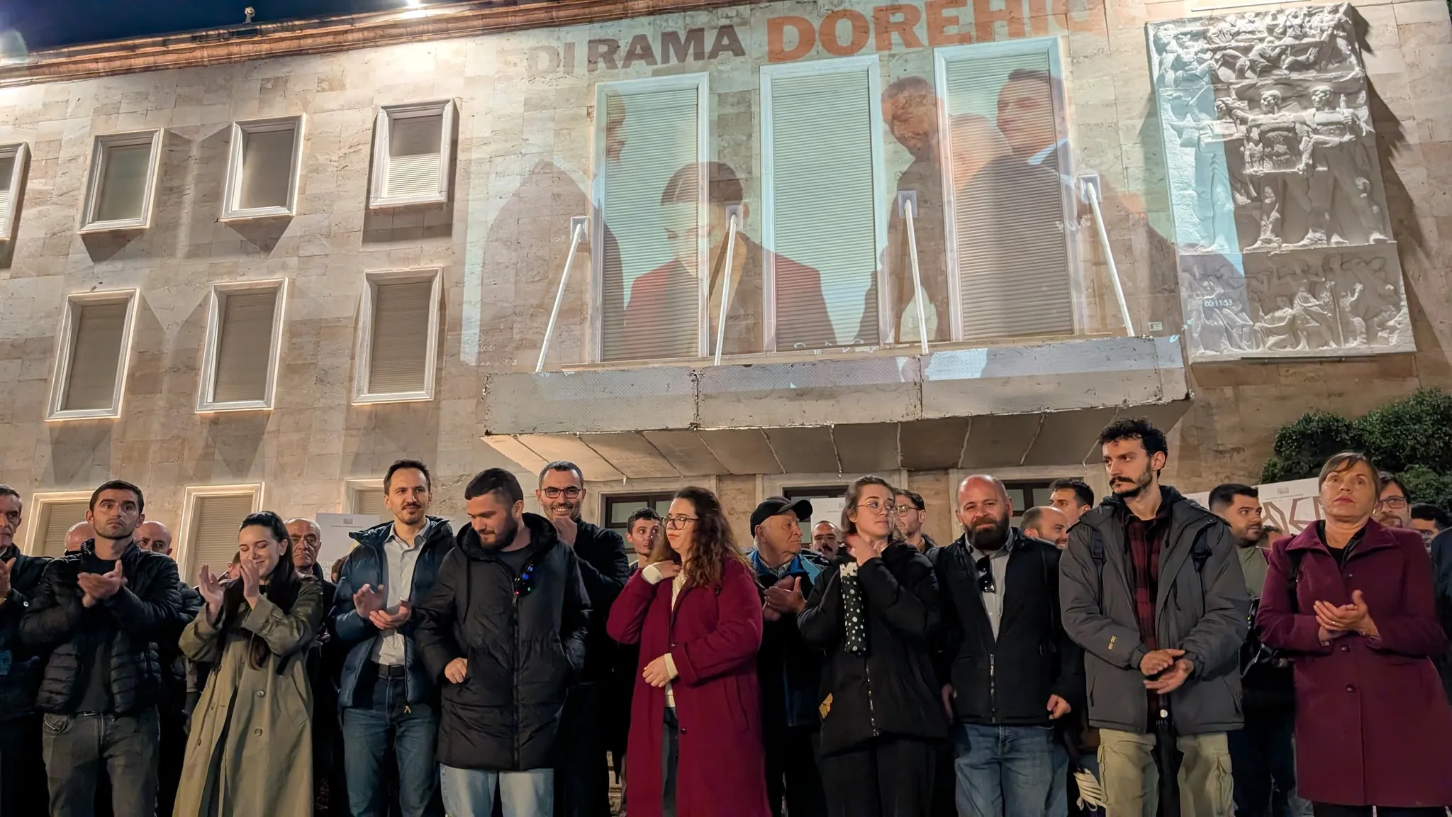 Aktivistët e Lëvizjes BASHKË gjatë komunikatës para kryeministrisë ku kërkojnë dorëheqjen e Edi Ramës. Ne sfond, projektuar ne fasadën e godinës se KM nje montath me Ramën, Ballukun dhe Veliajn me mbishkrimin 'Edi Rama dorëhiqu!'