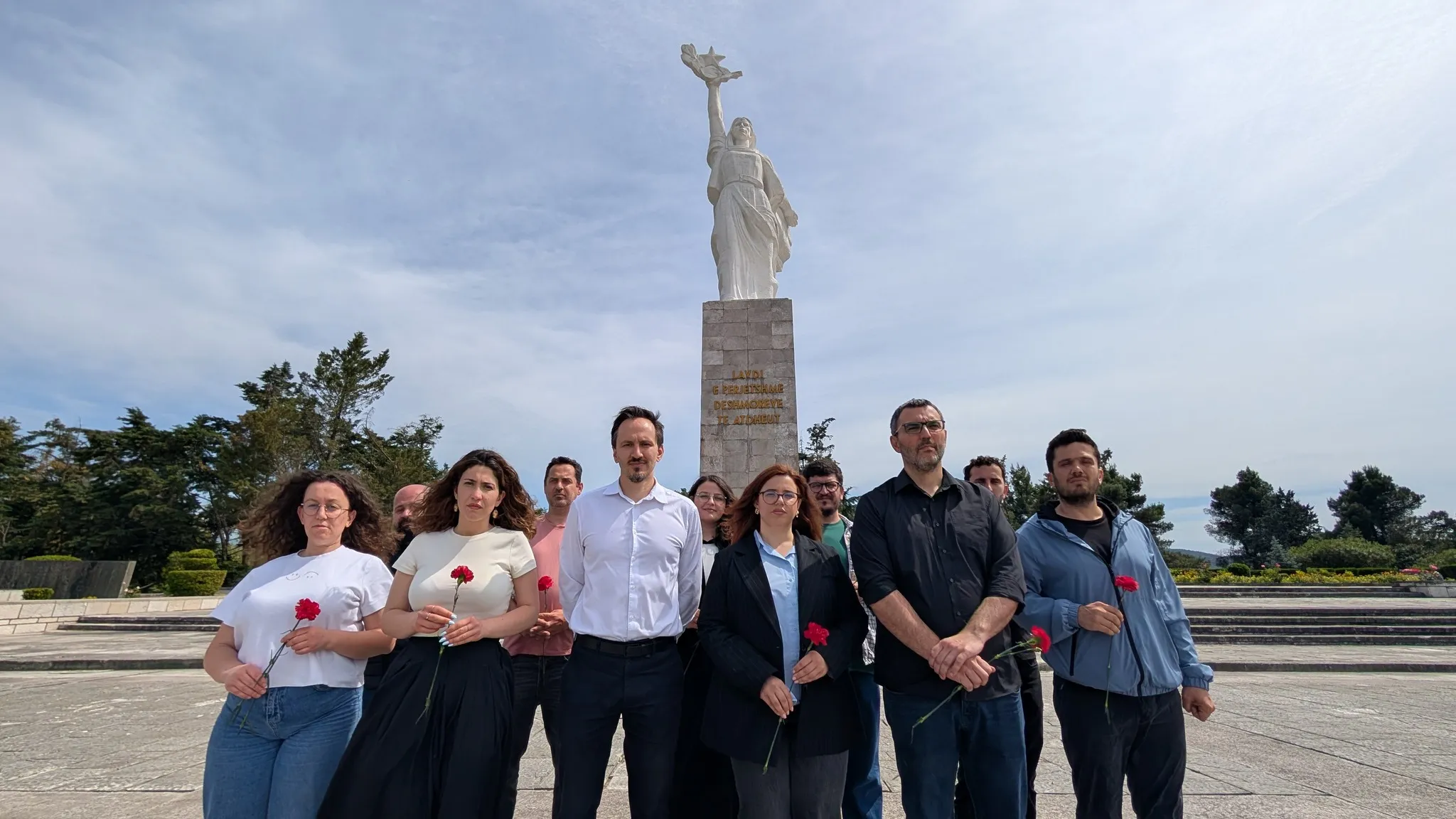 Aktivistët e LB me karafila të kuq në dorë, përpara monumentit të Nënës Shqipëri në Varrezat e Dëshmorëve